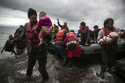 Un migrante lleva a su bebé en brazos después de cruzar el mar Egeo desde Turquía.