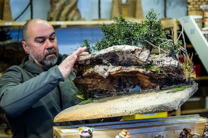 Lino Ferreira enseña una de las cuevas que elaboran para decorar los belenes en su puesto de la Plaza Mayor. Están hechas a partir de corcho de alcornoque y musgo natural, con hojas de plástico tratado.