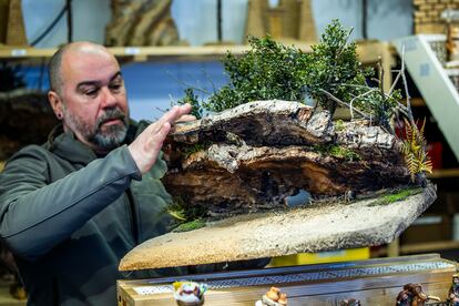 Lino Ferreira enseña una de las cuevas que elaboran para decorar los belenes en su puesto de la Plaza Mayor. Están hechas a partir de corcho de alcornoque y musgo natural, con hojas de plástico tratado.