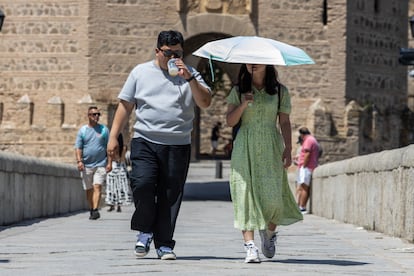 Turistas se protegen del sol durante la ola de calor en Toledo, este domingo.