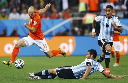 Robben se impone con el bal&oacute;n ante Garay, en el suelo, y Marcos Rojo (d), de la selecci&oacute;n argentina.