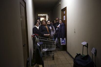 Un grupo de gente espera su ración de pan, arroz, azúcar y demás, en la mitad del pasillo del banco de alimentos.