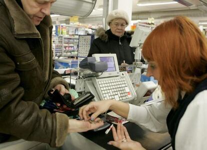 Una cajera ayuda a un cliente a contar las monedas de euro en un supermercado.