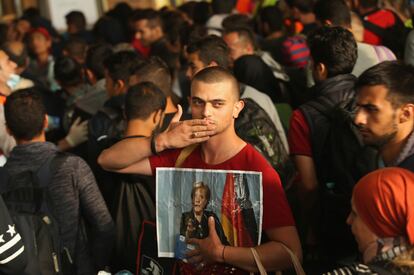 Un migrante sirio, con una foto de Merkel, tras llegar a Alemania desde Hungría durante la crisis migratoria de 2015.