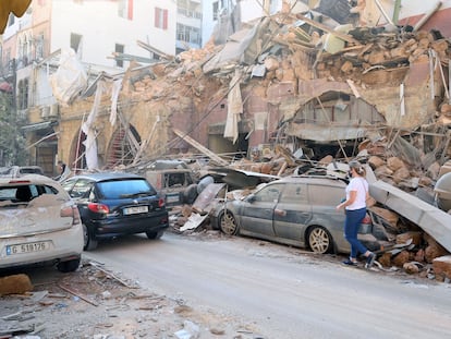 Una mujer camina este miércoles junto a edificios y vehículos dañados por la deflagración del martes en Beirut.