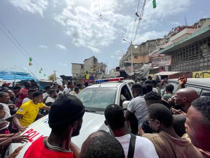 Decenas de personas se aglomeran en torno a un automóvil de la Policía en el que hay dos colombianos capturados por un grupo de personas en Puerto Principe (Haití).