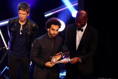 El jugador del Liverpool Mohamed Salah recibe el premio Puskas de manos de Didier Drogba y el músico Noel Gallagher.
