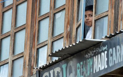 Un niño de Cachemira (India) mira desde una ventana del piso superior de una vivienda cómo un grupo de manifestantes locales grita consignas contra los indios y protesta por el asesinato de civiles y el toque de queda.