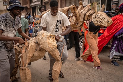 Un grupo de titiriteros y artistas locales caminan junto a títeres de animales a escala real por las calles del barrio de Ouakam, en Dakar, como parte del proyecto de arte participativo y acción climática ‘The Herds’. Aunque los prototipos de cada animal han sido concebidos en Sudáfrica por el colectivo Ukwanda Puppets and Designs, las marionetas son fabricadas en las ciudades que visitan por artistas locales.
