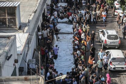 Decenas de personas rodean los cuerpos de mueros durante los bombardeos israelíes en la franja de Gaza.