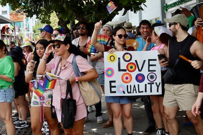 Asistentes a la Marcha del Orgullo sostienen abanicos, pancartas y banderas en defensa de la igualdad.