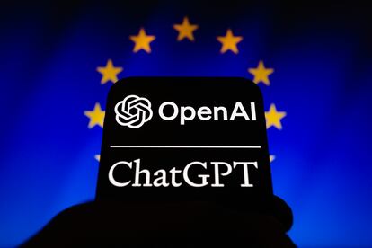 Los logos de OpenAI y ChatGPT en un teléfono móvil frente a un cartel con la bandera de la UE.