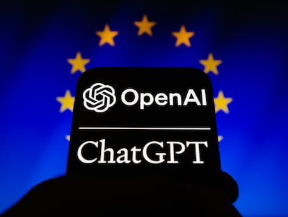 Los logos de OpenAI y ChatGPT en un teléfono móvil frente a un cartel con la bandera de la UE.