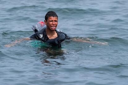 Un niño marroquí llora mientras nada usando botellas como flotador, cerca de la valla entre la frontera de España con Marruecos, después de que miles de migrantes cruzaran a nado, en Ceuta, el 19 de mayo de 2021.