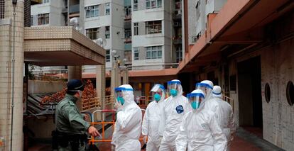 Policías con trajes protectores momentos antes de evacuar a residentes de un edificio de vivienda pública en Hong Kong.