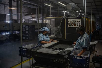 Dos mujeres trabajan en la fabricación de controles remotos para la televisión, en Tijuana, en 2021.