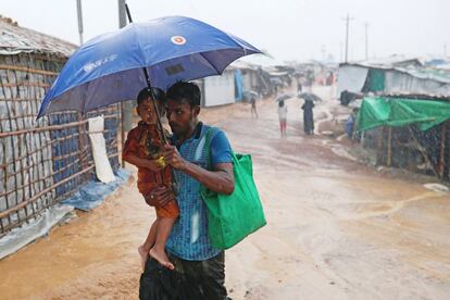Un hombre y su hijo intentan llegar a su casa en el campamento de Kutupalong bajo una intensa lluvia.