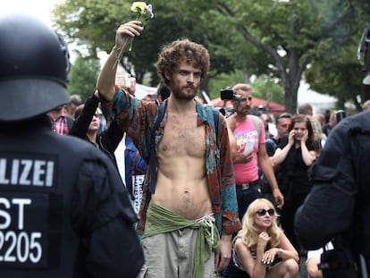 Homem segura uma flor durante manifestação contra as medidas de combate a coronavírus, neste sábado, em Berlim.