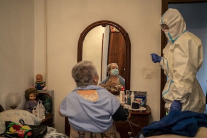 La médico residente Joana Ugalde atiende a Isabel, de 79 años, en su piso de Madrid. La paciente presenta problemas respiratorios.