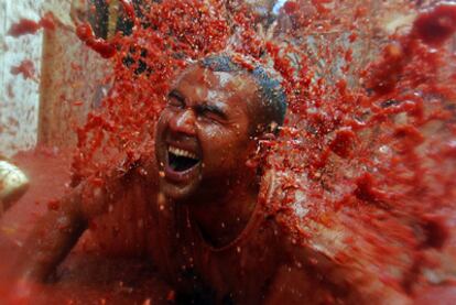 Un participante recibe una explosión de zumo de tomate sobre su cuerpo durante la fiesta de la Tomatina de Buñol.