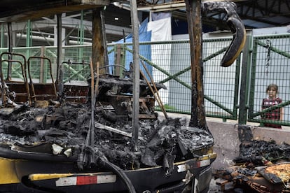 Un niño observa los restos de un autobús quemado en Guayaquil.