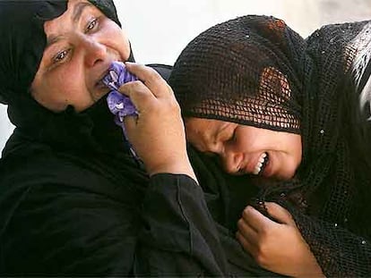 Dos mujeres lloran la muerte de un familiar en la explosión de dos bombas en un campo de fútbol el miércoles en Bagdad.