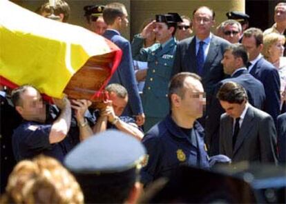 José María Aznar, a la derecha, cabizbajo al paso del ataúd de uno de los dos policías asesinados ayer, durante el funeral en Pamplona.