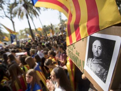 Hundreds of people congregate at a courthouse in Barcelona, and one person holds up a photo of Franco.
