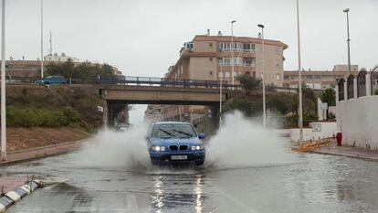 Un vehículo circula por una calle inundada en la zona del Parque de las Naciones de Torrevieja (Alicante).