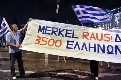 Un manifestante sujeta una pancarta que dice &quot;fuera Merkel&quot; en Atenas.