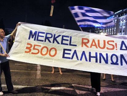 Un manifestante sujeta una pancarta que dice "fuera Merkel" en Atenas.