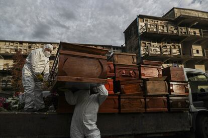 Unos trabajadores recogen y apilan los ataúdes de personas que han sido incineradas recientemente tras haber fallecido por el coronavirus, en el cementerio de La Recoleta en Santiago de Chile.