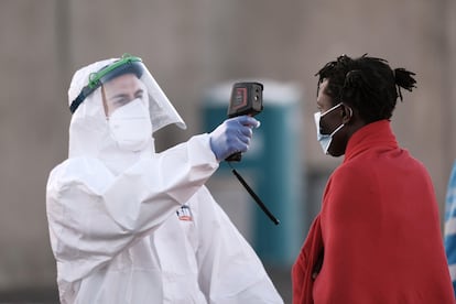 Un sanitario toma la temperatura a uno de los 52 hombres de origen subsahariano rescatados en el Mediterráneo y trasladados al puerto de Arguineguín (Gran Canaria) el pasado 20 de marzo.