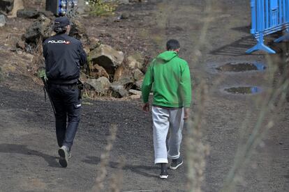 VALVERDE (EL HIERRO), 16/10/2024.- Un inmigrante pakistaní llegado en cayuco a El Hierro camina junto a un agente por el centro de atención temporal de extranjeros (CATE) de San Andrés, en Valderde, una instalación policial donde los recién llegados son retenidos hasta 72 horas para su filiación. EFE/Gelmert Finol