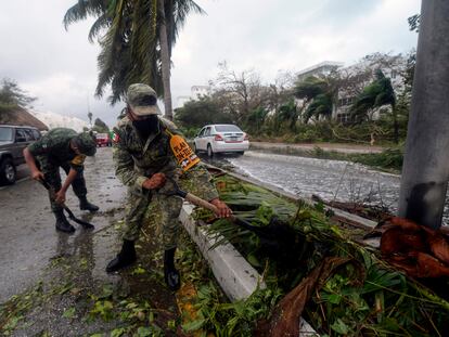 Miembros del Ejército quitan los restos de árboles caídos tras el paso del huracán Delta por Cancún.