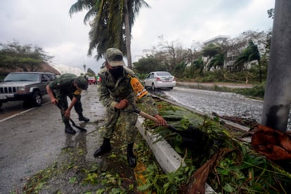 Miembros del Ejército quitan los restos de árboles caídos tras el paso del huracán Delta por Cancún.