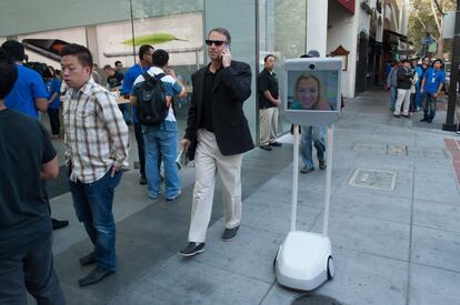 Un robot cruza frente a una fila de clientes que buscan comprar el iPhone6 en una tienda de Apple en Palo Alto, California (EE.UU.).