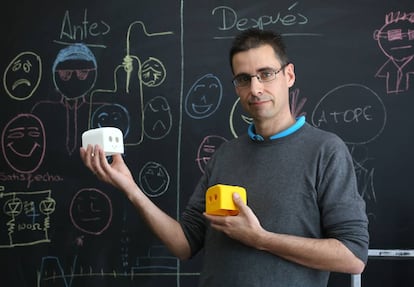 Juan González sostiene dos piezas de robots diseñadas por él mismo.