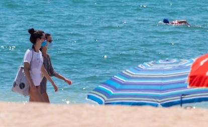 Dos mujeres pasean por la playa de La Antilla (Huelva) con mascarilla.