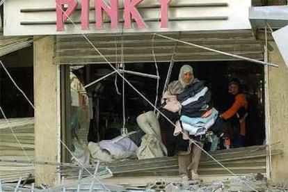 Dos mujeres se llevan ropa de una tienda de Beirut afectada por los bombardeos israelíes.