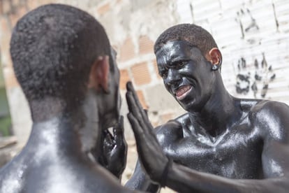 Rapazes se pintam com tinta e mel de cabaú na festa dos Lambe Sujos