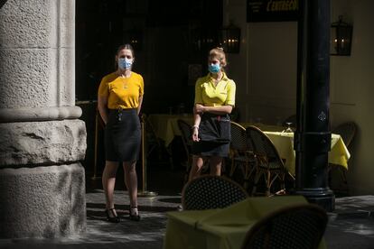 Dos camareras junto a la terraza sin clientes del bar donde trabajan, en el centro de Barcelona. 