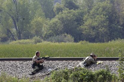 Police officers patrol a swampy area in Fox Lake, Ill., during a manhunt after an officer was shot and killed while pursuing a group of suspicious men, Tuesday, Sept. 1, 2015. Authorities in Fox Lake, 55 miles north of Chicago,  have notified a number of other law enforcement agencies to ask for assistance, including the FBI, which is sending agents to help in the investigation. (Stacey Wescott/Chicago Tribune via AP) MANDATORY CREDIT CHICAGO TRIBUNE; CHICAGO SUN-TIMES OUT; DAILY HERALD OUT; NORTHWEST HERALD OUT; THE HERALD-NEWS OUT; DAILY CHRONICLE OUT; THE TIMES OF NORTHWEST INDIANA OUT; TV OUT; MAGS OUT; NO SALES   