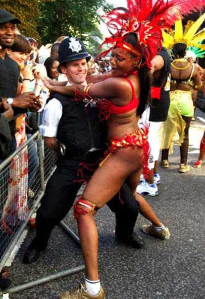 Una participante en el carnaval de Notting Hill baila con un policía.