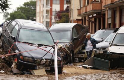 Una mujer habla por teléfono rodeada de vehículos destrozados por las lluvias, en Tafalla.