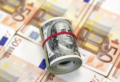 Un rollo de billetes de dólar, junto a otros de 50 euros.