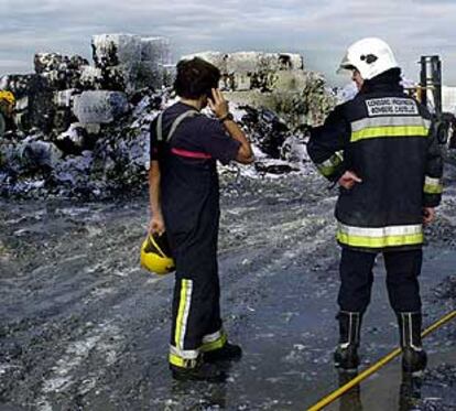 Dos bomberos, ayer, durante la extinción del papel almacenado.