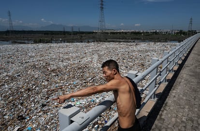 Un hombre inspecciona una gran área de basura traída por las inundaciones en el río Yongding, en China.