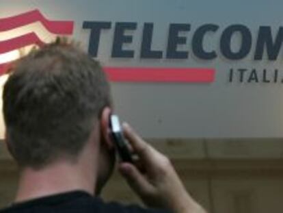 Un hombre hablando por el m&oacute;vil frente a una tienda de Telecom Italia.