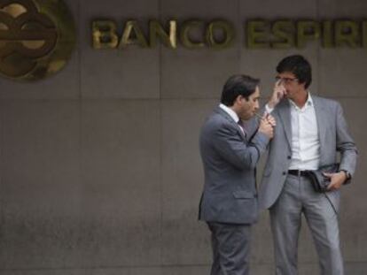 Dos hombres charlan junto a la fachada del Banco Esp&iacute;rito Santo en Lisboa.